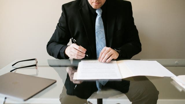 Professional real estate agent reviewing documents at desk in modern office setting.